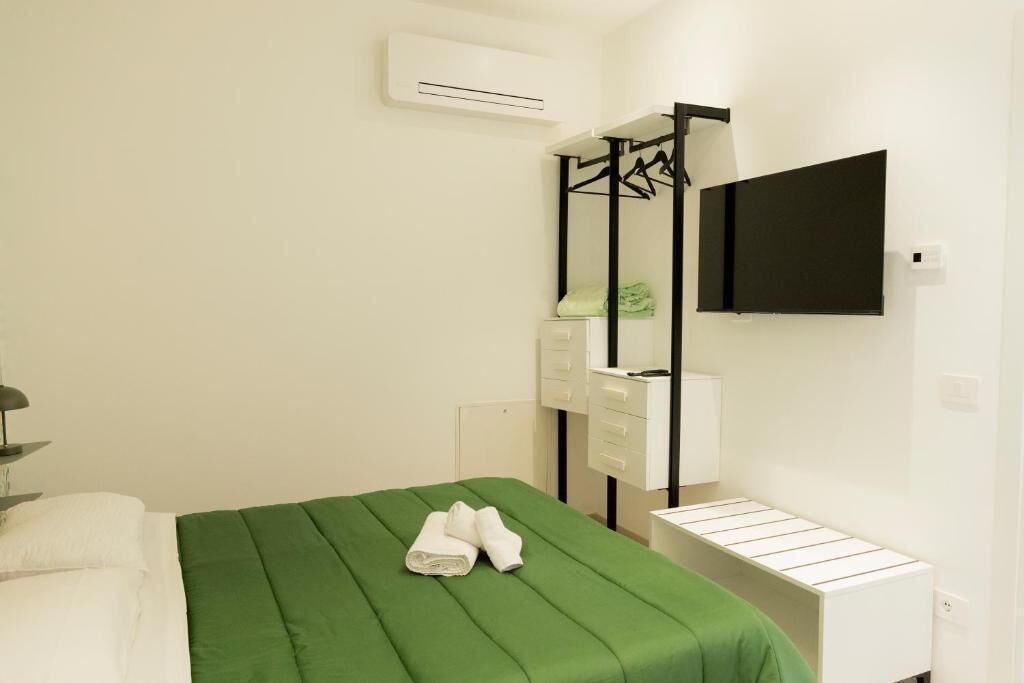 A hotel room with a bed, a mirror, a wardrobe, a TV, and a small table.