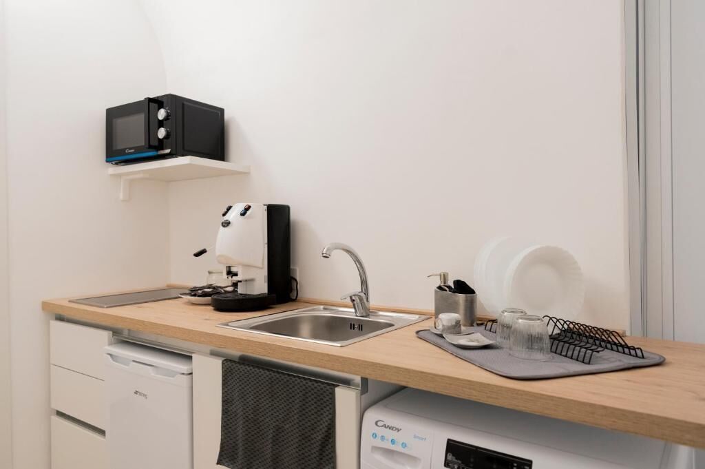 A compact kitchen with a microwave, coffee maker, sink, and dishwasher.