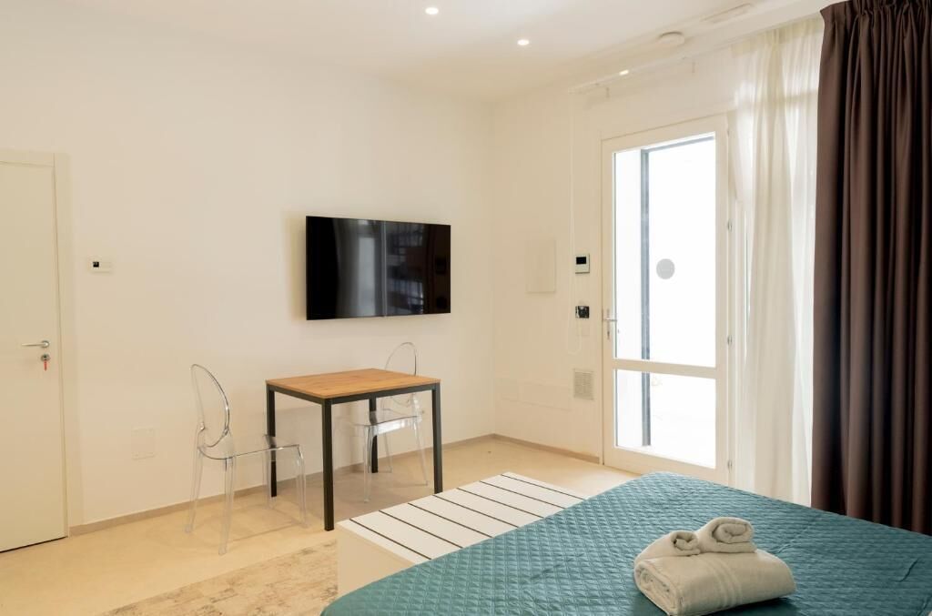 A hotel room with a bed, a TV, a small table, and a chair.