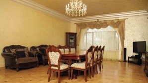 Ein Esszimmer mit Holztisch und -stühlen, einer Chandelier und einem Fernseher.