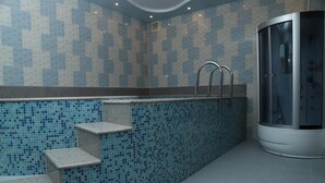 Ein modernes Badezimmer mit einer Mosaikfliesenwand, einer integrierten Dusche und einer Sauna mit Glastüren.