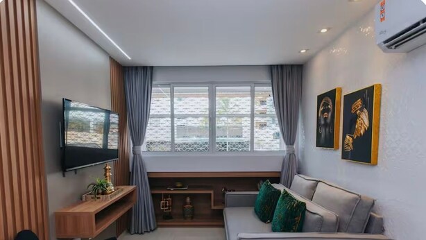 Een moderne woonkamer met een bank, televisie en kunst aan de muur.
