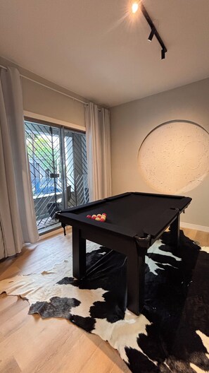 Et billardbord i et rum med en skydedør, en ko-læder måtte og en væg med struktur.