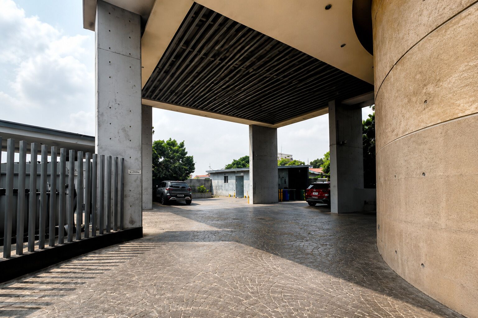 A parking area with concrete pillars, a metal fence, and a paved ground.
