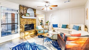 A living room with a fireplace, a ceiling fan, a sofa, and a coffee table. - Cozy Frisco Getaway - Fireplace + Relaxing Backyard (Frisco)