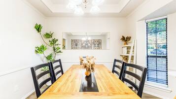 Ein Esszimmer mit Holztisch, schwarzen Stühlen, einer Kronleuchter und Wanddekoration.
