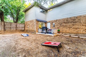 A backyard with a patio, a brick wall, and a wooden fence. - Cozy Frisco Getaway - Fireplace + Relaxing Backyard (Frisco)
