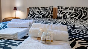 Un lit bien fait, recouvert d’une couvre-lit à motifs zébrés, avec une lampe et des articles de toilette posés sur le lit.