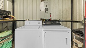 A laundry room with two washing machines, a utility meter, and a shelf with various items. - Cozy Cottage - Direct access to Brimstone Trails - Multiple Hot Tubs- Fire Pits (Huntsville)