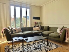 Een woonkamer met een hoekbank, een salontafel en een kamerkleed met patroon.