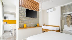 Una habitación de hotel moderna con una cama, una kitchenette pequeña, un televisor y paredes con diseño.