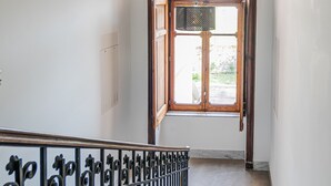 Una escalera con barandilla de metal, una puerta de madera y una ventana de arco.