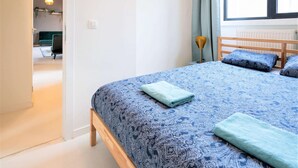 Ein Schlafzimmer mit einem Bett, einem Fenster und einer Tür zu einem anderen Raum.