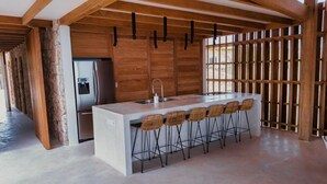 Una cucina moderna con isola centrale, sgabelli da bar, frigorifero e dispenser d'acqua.