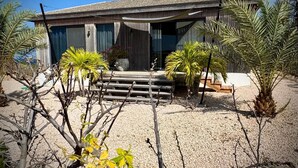 Una casa moderna con un'ampia vetrata, un patio in legno e palme.