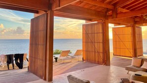 Un pontile in legno con poltrone relax e vista sul mare.