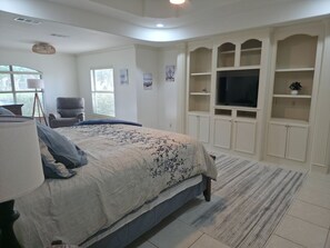 A bedroom with a bed, a chair, a TV, and built-in shelving. - Spacious 4-bedroom home in Laguna Vista w/pool, pickleball, golf course and gym (Laguna Vista)