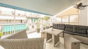 A covered outdoor seating area with wicker furniture, a table, and a sofa. - Athens Spacious Penthouse - City Center & Metro (Athina)