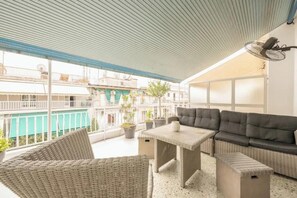 A covered outdoor seating area with wicker furniture, a table, and a sofa. - Athens Spacious Penthouse - City Center & Metro (Athina)