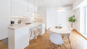 A modern kitchen with a central island, bar stools, pendant lighting, and a dining table with chairs. - Athens Spacious Penthouse - City Center & Metro (Athina)