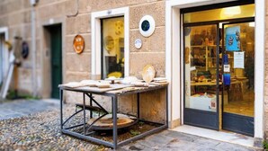 A building with a stone facade, numbered 91, and a table outside with various items on it. - [Sea 3m] Trains 8m • A/C • FreeWiFi (Albisola Superiore)