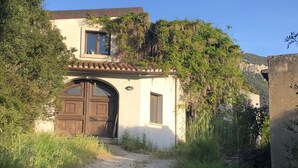 A rustic building with a large wooden door, a small window, and a tiled roof.
