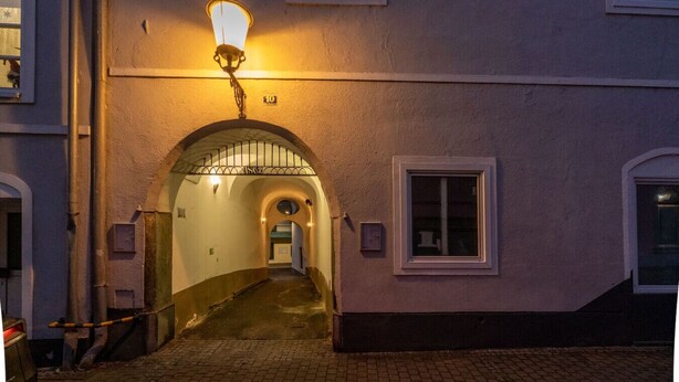 A narrow alleyway with a street lamp, an arched entrance, and a building with a window. - Stylish Apartment at Main Square - 35 m² - Quiet (Leoben)