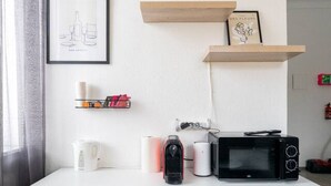 A white dresser with drawers, a framed picture, a shelf with books and a candle, and a microwave on top. - Stylish Apartment at Main Square - 35 m² - Quiet (Leoben)