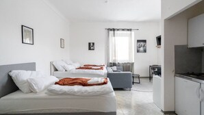 A modern hotel room with two beds, a kitchenette, and a dining area. - Stylish Apartment at Main Square - 35 m² - Quiet (Leoben)