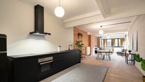 Una cocina moderna con encimera negra, horno empotrado y campana extractora de acero inoxidable.