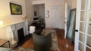 A living room with a fireplace, a green armchair, a dining table, and a kitchen area with a microwave.