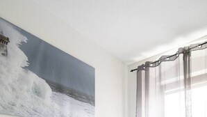 A modern bedroom with a bed, a bedside table, a nightstand, a window with curtains, and a painting on the wall. - Modern Apartment - Main Square - 30 m² - Comfort (Leoben)