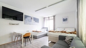 A modern hotel room with a bed, a sofa, a desk, and a TV. - Modern Apartment - Main Square - 30 m² - Comfort (Leoben)