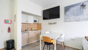 A compact living space with a kitchenette, a dining area, and a mounted TV. - Modern Apartment - Main Square - 30 m² - Comfort (Leoben)