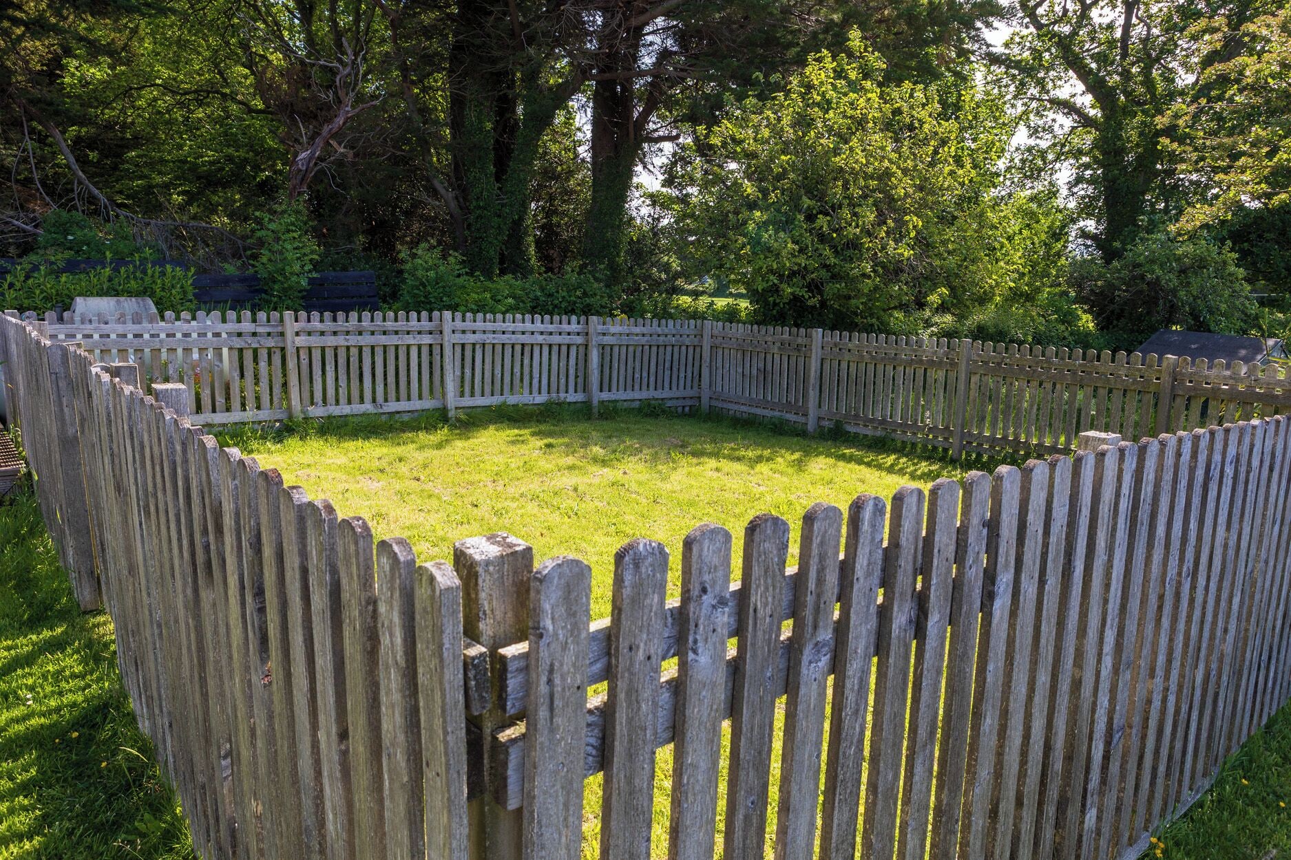 Une clôture circulaire en bois entourant une zone herbeuse.
