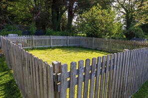 A circular wooden fence surrounding a grassy area. - Eryri View Retreat (Beaumaris)