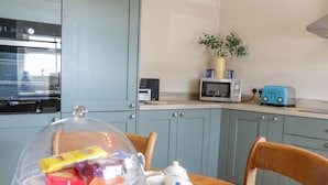 A kitchen with a microwave, toaster, and cabinets. - Eryri View Retreat (Beaumaris)