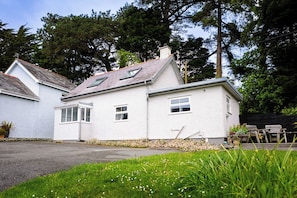 A two-story house with a sloped roof, white exterior walls, and multiple windows. - Eryri View Retreat (Beaumaris)