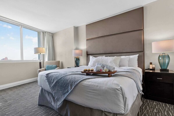 Ein Hotelzimmer mit einem großen Bett, einem Nachttisch, einer Lampe und Blick zum Himmel.