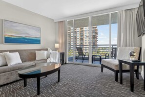 A hotel room with a sofa, armchair, coffee table, and a balcony with a view of high-rise buildings. - Gallery One  Spa  Heated Pool   Boat Taxi (Fort Lauderdale)
