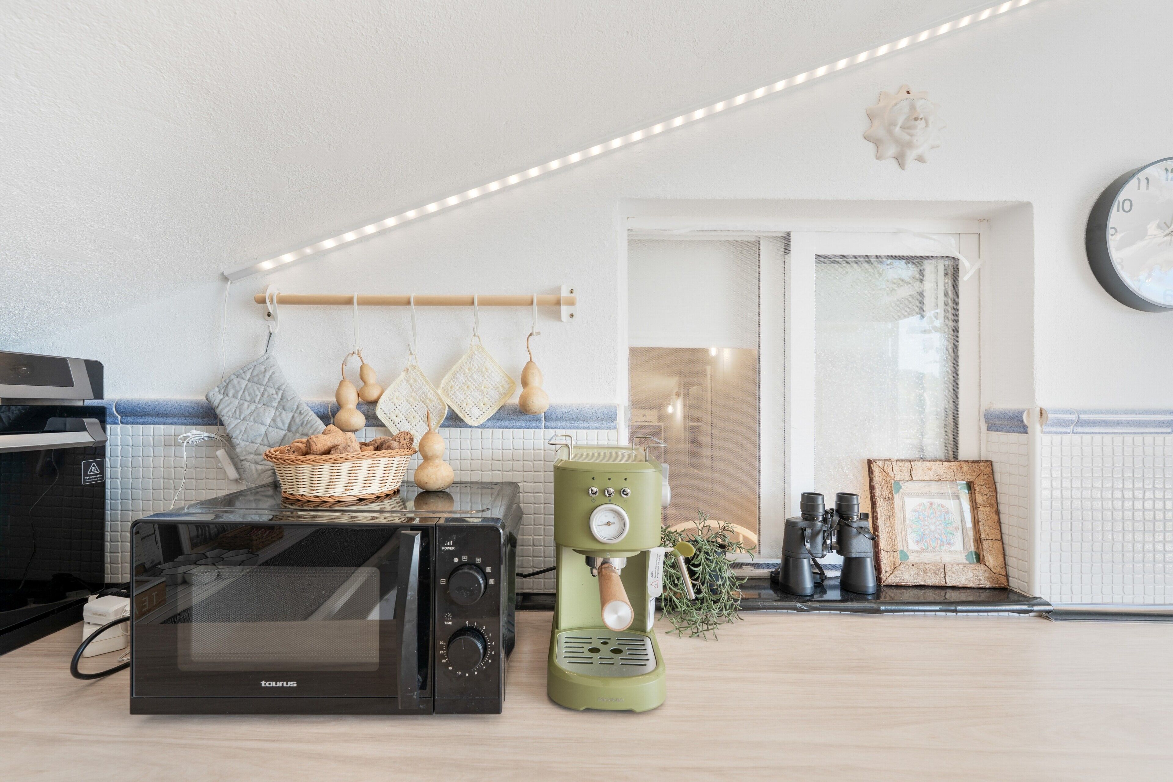 A kitchen with a microwave, coffee maker, and hanging kitchen tools.