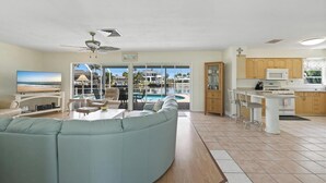 Ein Wohnzimmer mit Fernseher, Sofa und Essbereich mit Blick auf einen Pool und ein Resort.