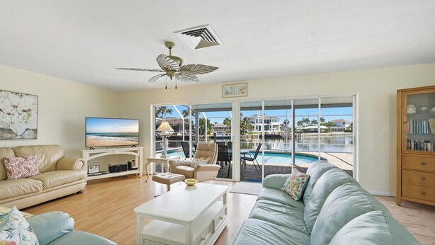 Ein Wohnzimmer mit Fernseher, Sofa, Couchtisch und Blick auf Pool und Strand.