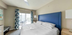 Ein Hotelzimmer mit einem großen Bett, einem Schreibtisch, einem Stuhl und einem Balkon mit Aussicht.