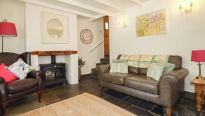 A cozy living room with a fireplace, a sofa, a chair, and a rug. - Millies Place (St Austell)