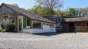 A building with a sloped roof, a gravel driveway, and a wooden fence. - Millies Place (St Austell)