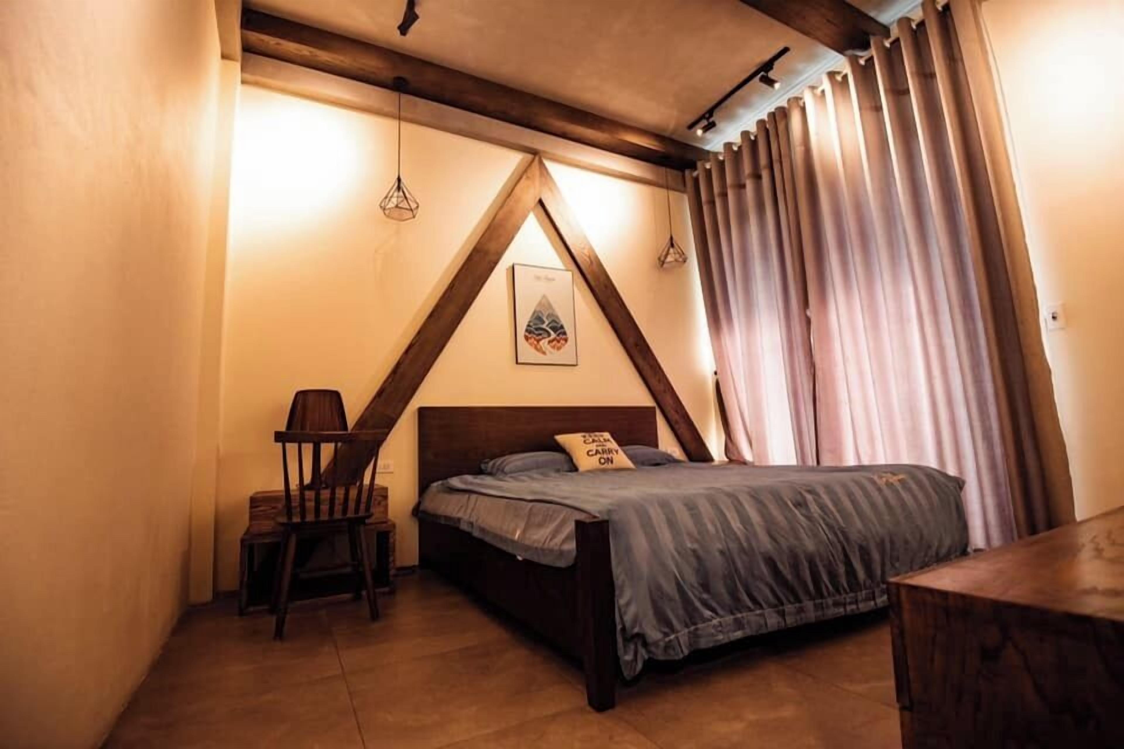 Un dormitorio con cama, una silla, un escritorio y un cuadro en la pared.