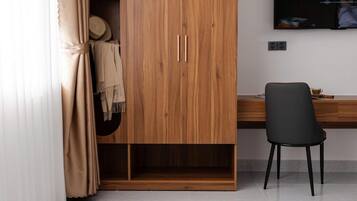 A modern bedroom with a wooden wardrobe, a desk, a chair, and a television.