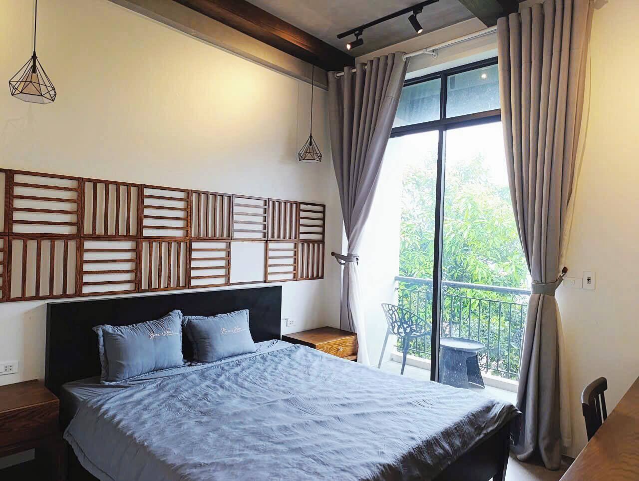 A bedroom with a bed, a nightstand, a window with curtains, and a view of greenery outside.