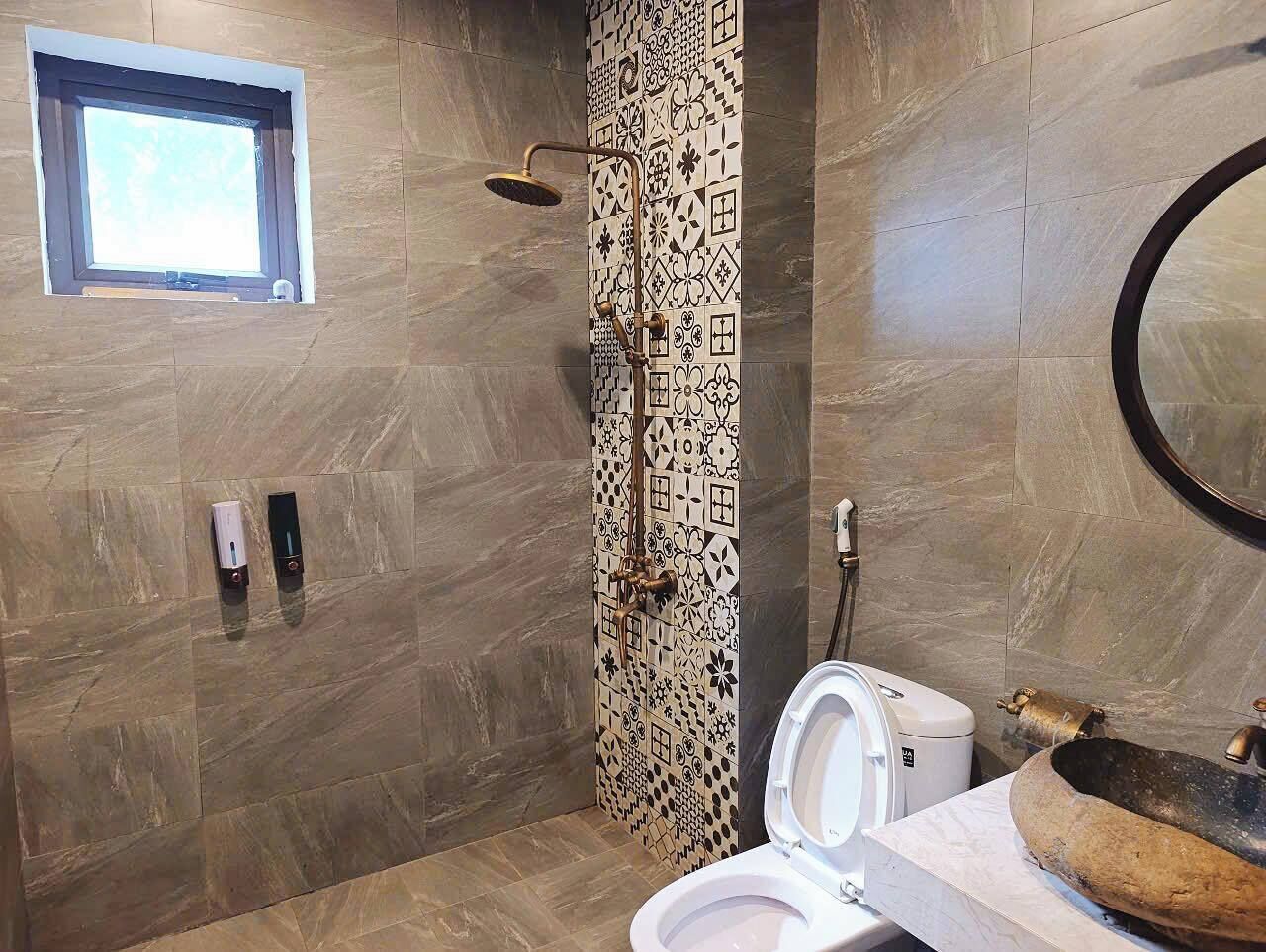A bathroom with a shower, toilet, and a window.